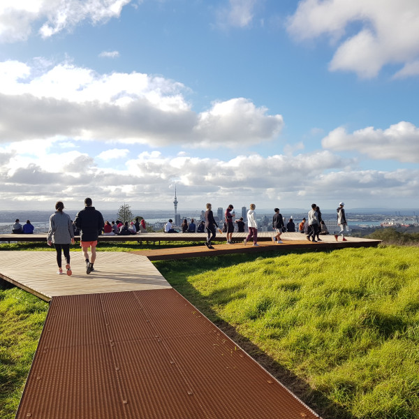 People on a boardwalk with view to harbour and Sky Tower